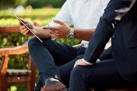 Deux hommes discutent autour d’une tablette dans un jardin